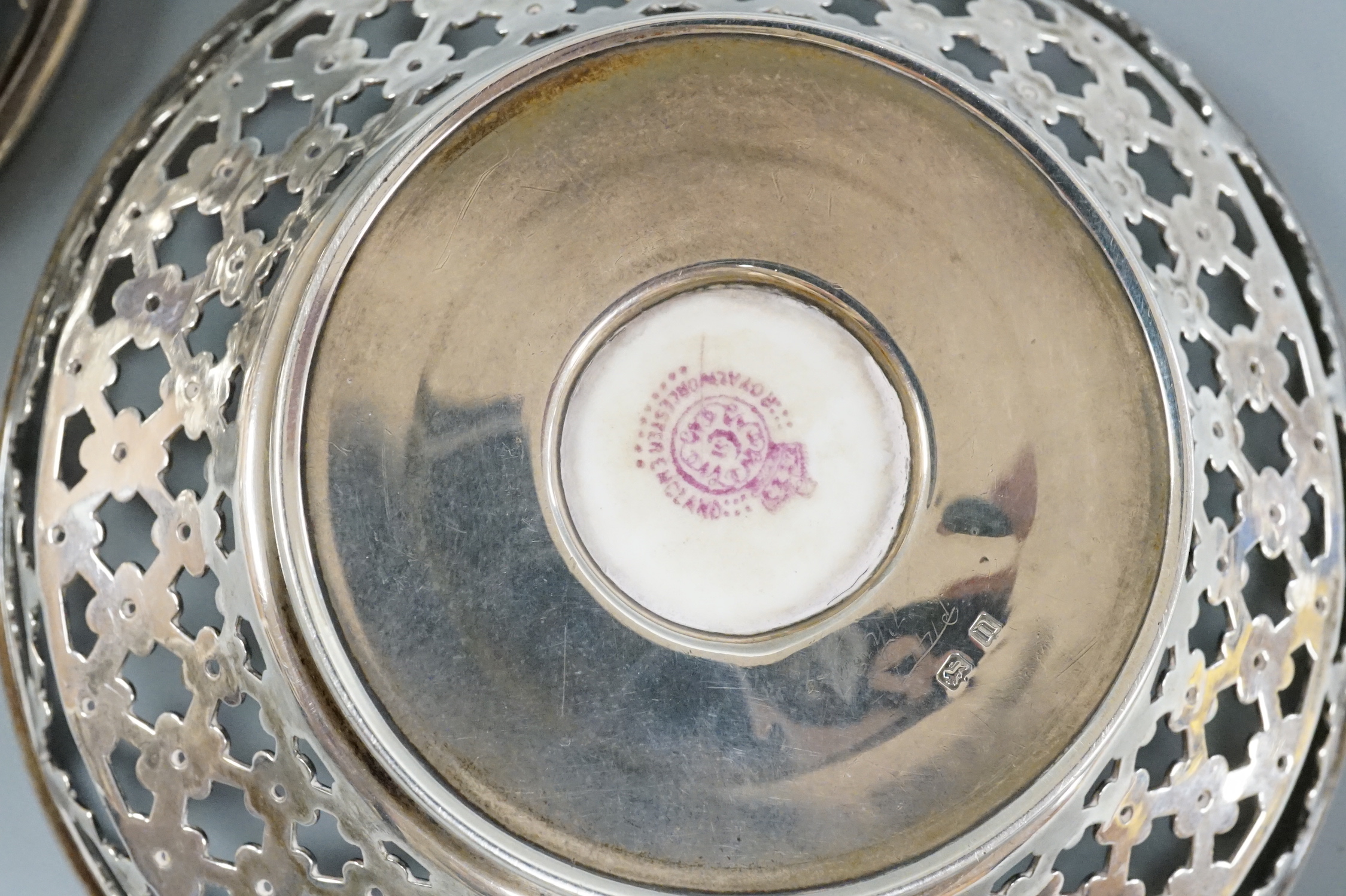 A pair of George V pierced silver mounted Royal Worcester panel bon bon dishes, painted by Raymond Rushton, hallmarked for Sanders & MacKenzie, Birmingham, 1912, diameter 10.5cm.